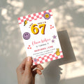 6 7 birthday invitation with bold 67 numbers, pink checkerboard border, happy face icons, retro flowers, purple stars and peace hand for a 7th birthday party.