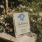 Minimalist first birthday invitation with blue bow illustration and soft neutral background