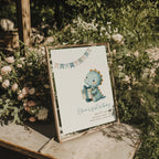 Dinosaur first birthday invitation with cute baby dinosaur holding a gift in soft pastel colors