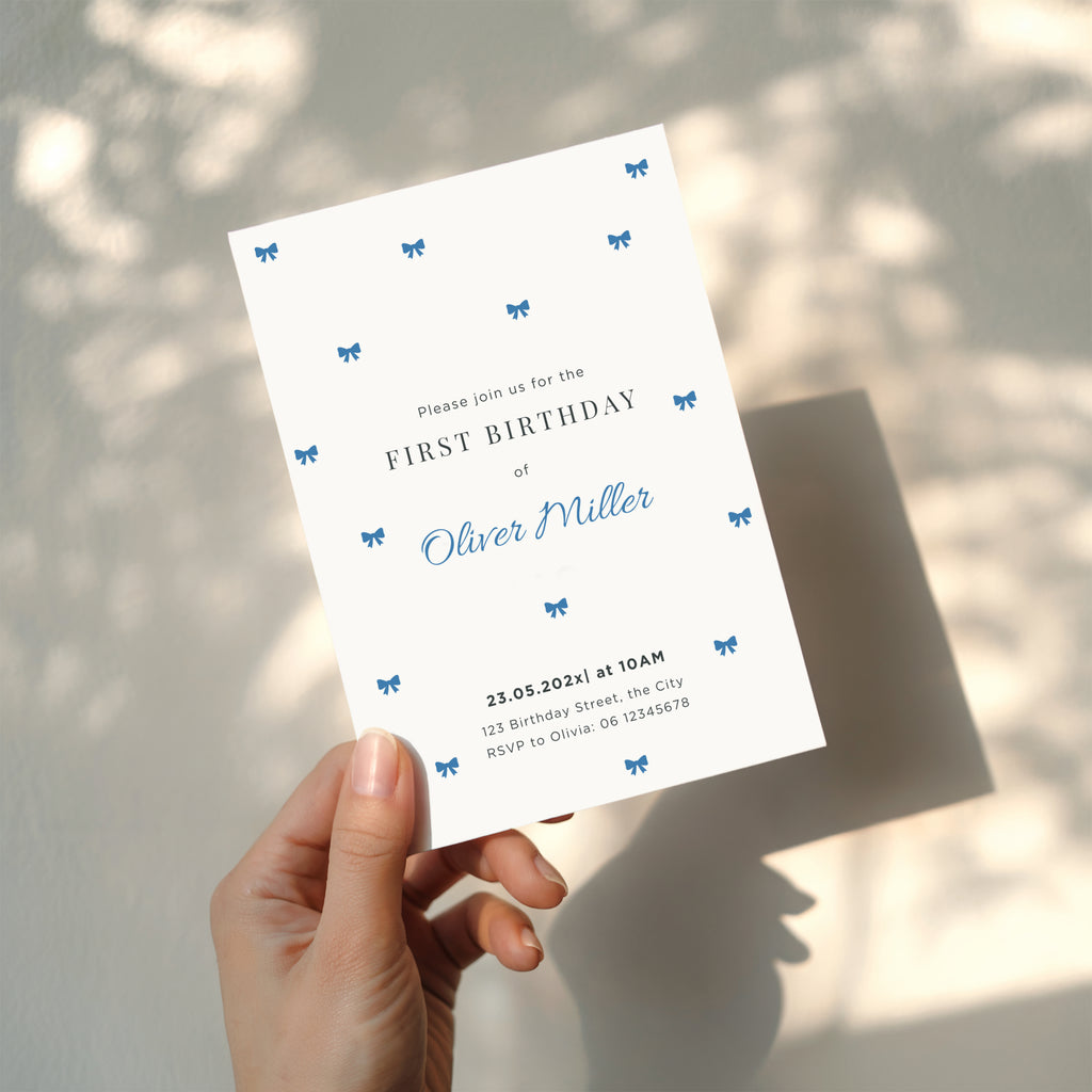 Minimal first birthday invitation with small blue bows and clean elegant design for a baby boy celebration