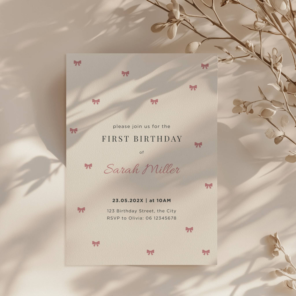 Minimal first birthday invitation with small pink bows and elegant clean design for a baby girl celebration
