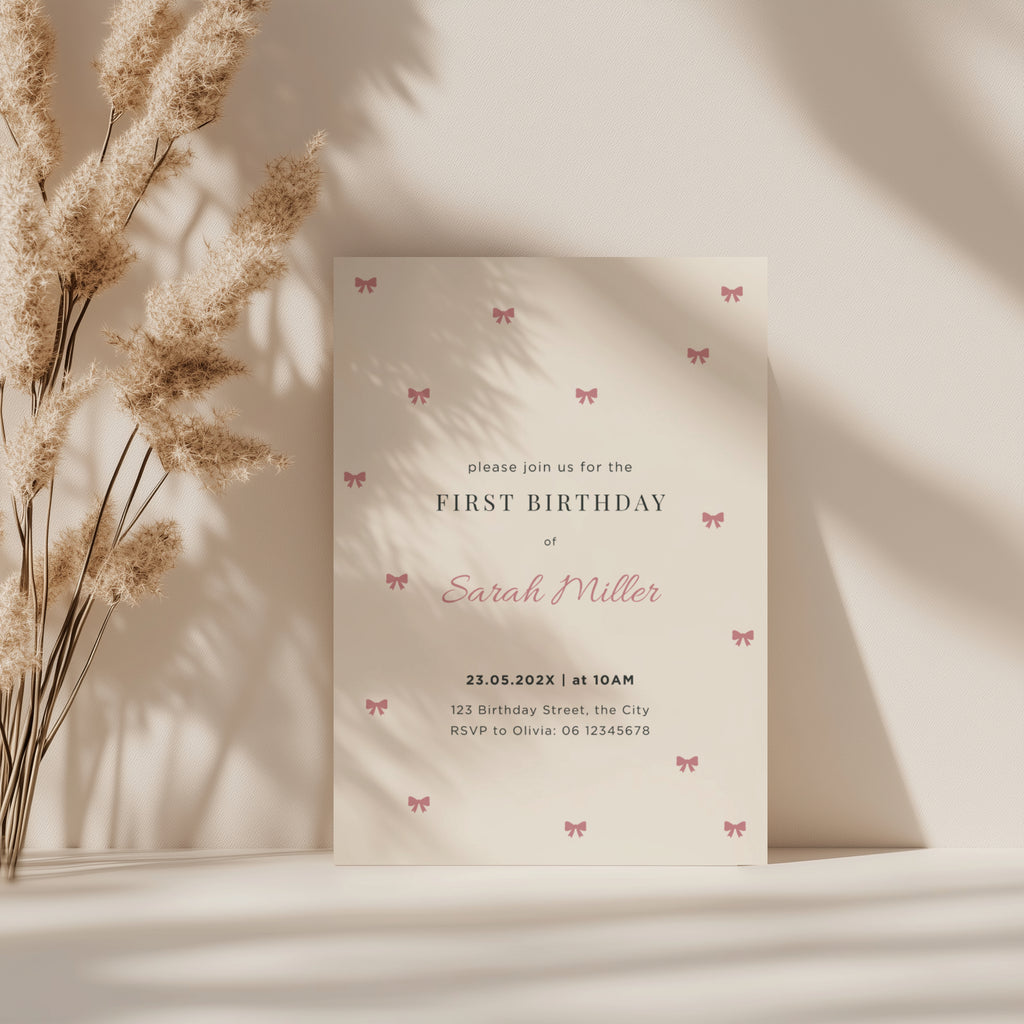 Minimal first birthday invitation with small pink bows and elegant clean design for a baby girl celebration