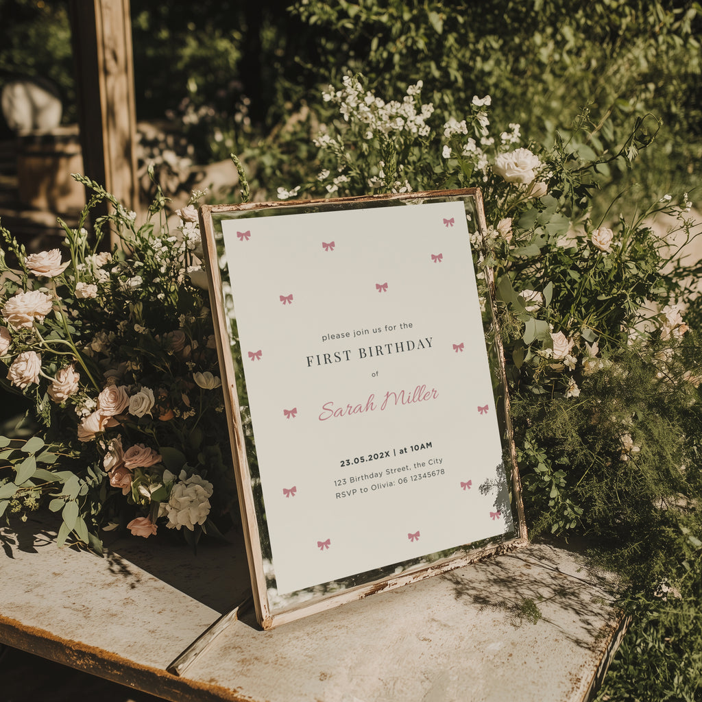 Minimal first birthday invitation with small pink bows and elegant clean design for a baby girl celebration