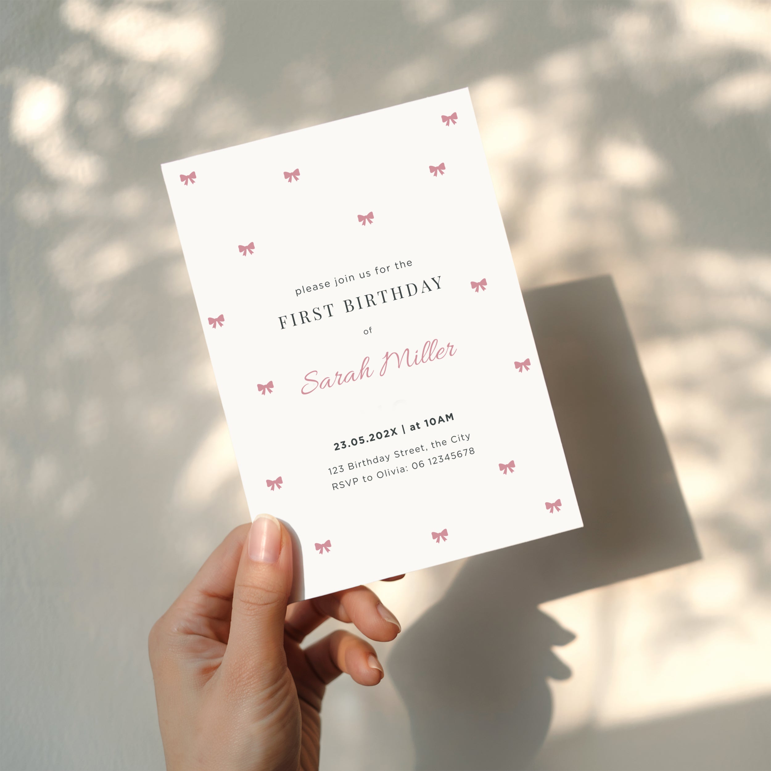 Minimal first birthday invitation with small pink bows and elegant clean design for a baby girl celebration
