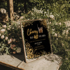 black and gold 40th birthday invitation with confetti, glowing text, and whiskey glass illustration