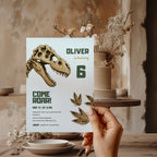 Editable dinosaur fossil birthday invitation featuring a realistic T-Rex skull and prehistoric footprints Canva template