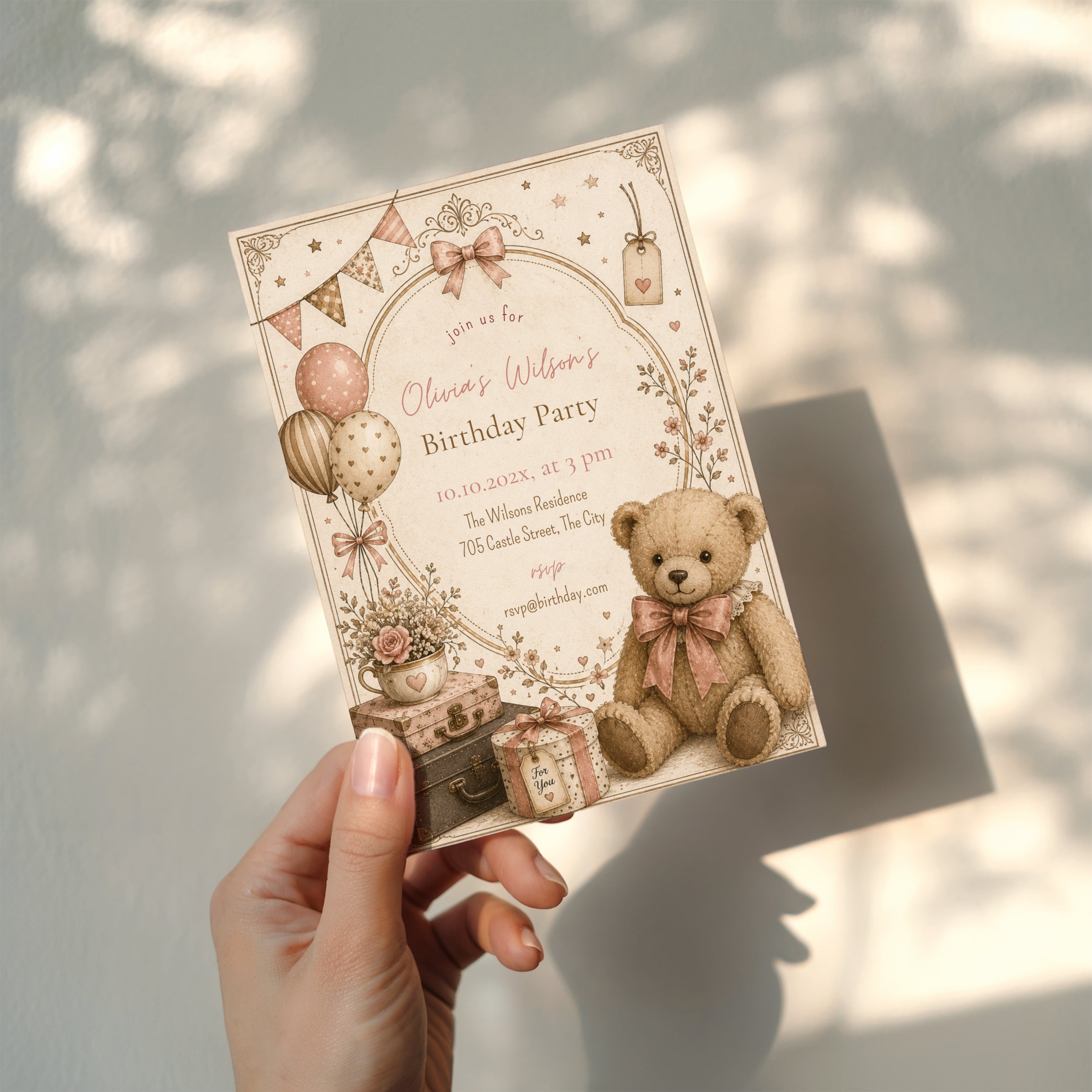 Vintage teddy bear birthday invitation with blush balloons, antique suitcases, delicate florals, and a soft storybook watercolor design for a child's birthday celebration.