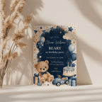 Classic Beary First birthday invitation featuring a teddy bear, blue balloons, birthday cake, vintage toy race car, and watercolor stars for a baby boy's first birthday.
