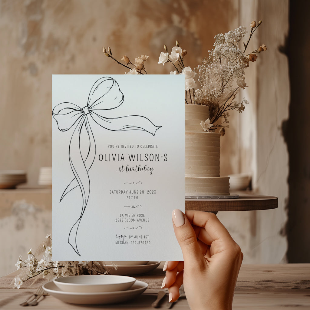 Minimalist black bow first birthday invitation with a hand-drawn ribbon, elegant black typography, and a clean white monochrome layout.