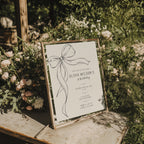 Minimalist black bow first birthday invitation with a hand-drawn ribbon, elegant black typography, and a clean white monochrome layout.