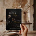 Boos and Booze Halloween party invitation featuring a skeleton holding a whiskey glass, black background, and amber typography for an adult Halloween party.