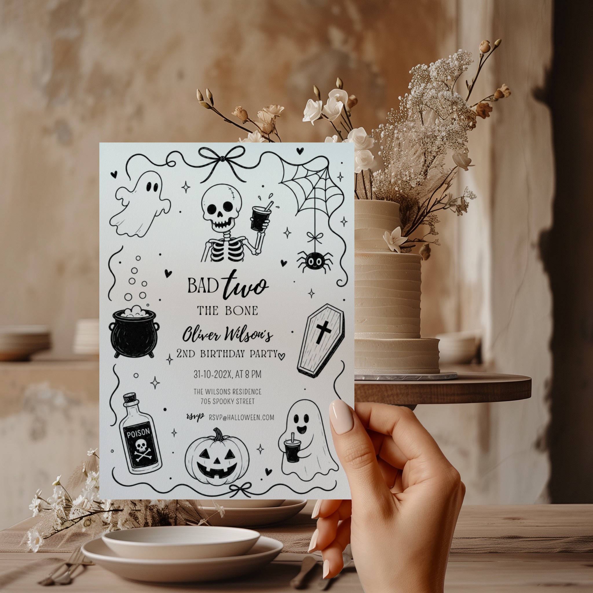 Bad Two the Bone birthday invitation for a second birthday with black and white skeleton, ghost, cauldron, coffin, spider and pumpkin illustrations.