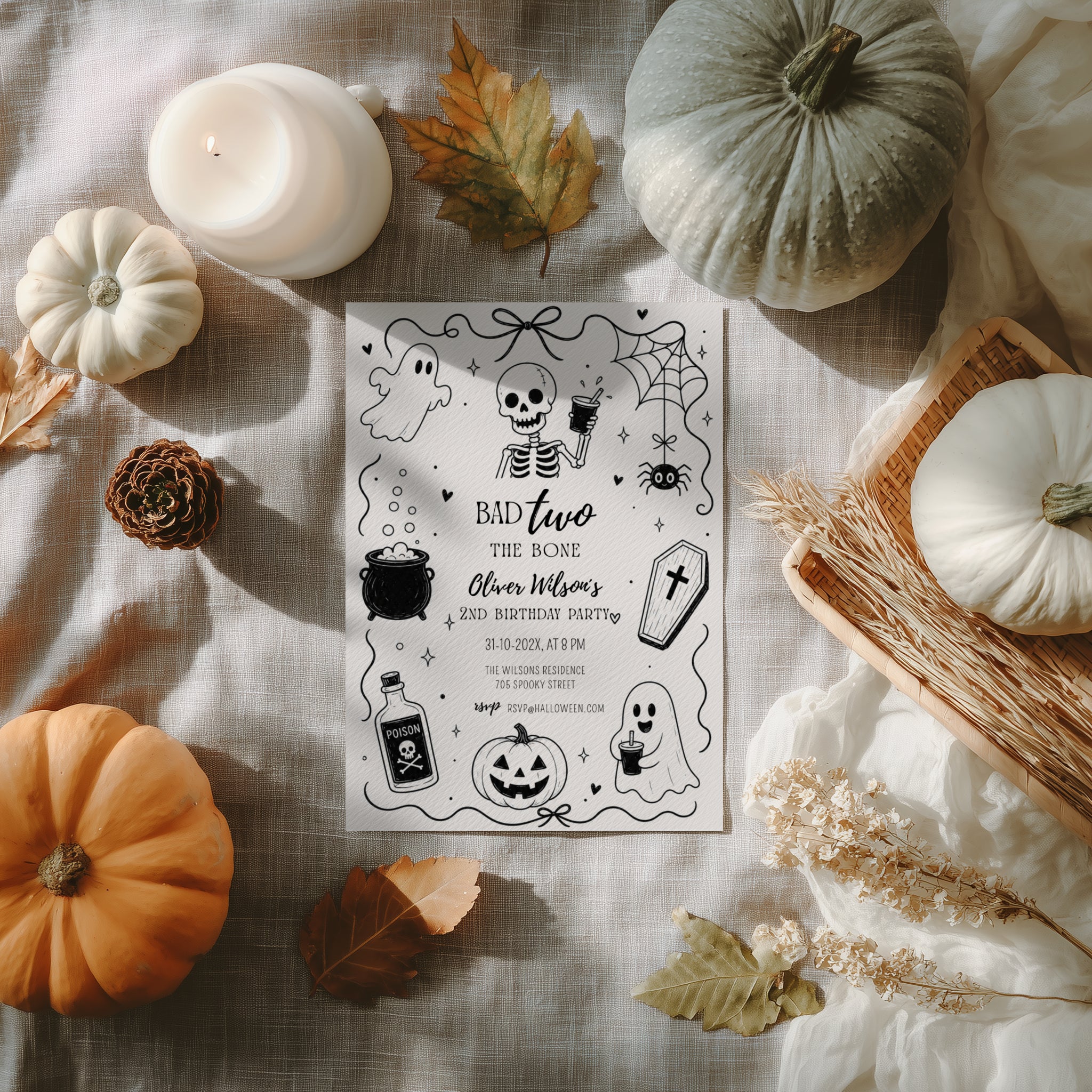 Bad Two the Bone birthday invitation for a second birthday with black and white skeleton, ghost, cauldron, coffin, spider and pumpkin illustrations.