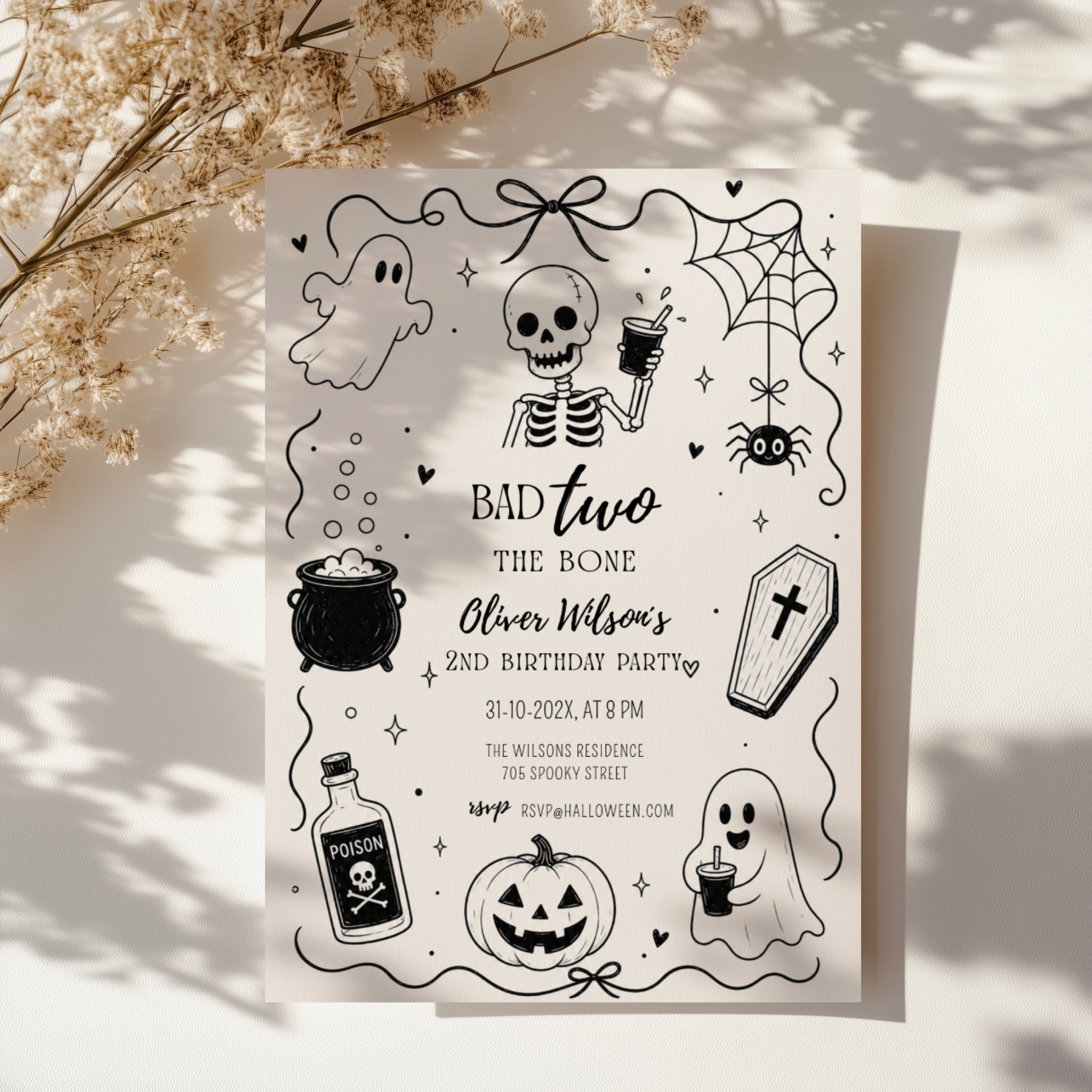 Bad Two the Bone birthday invitation for a second birthday with black and white skeleton, ghost, cauldron, coffin, spider and pumpkin illustrations.