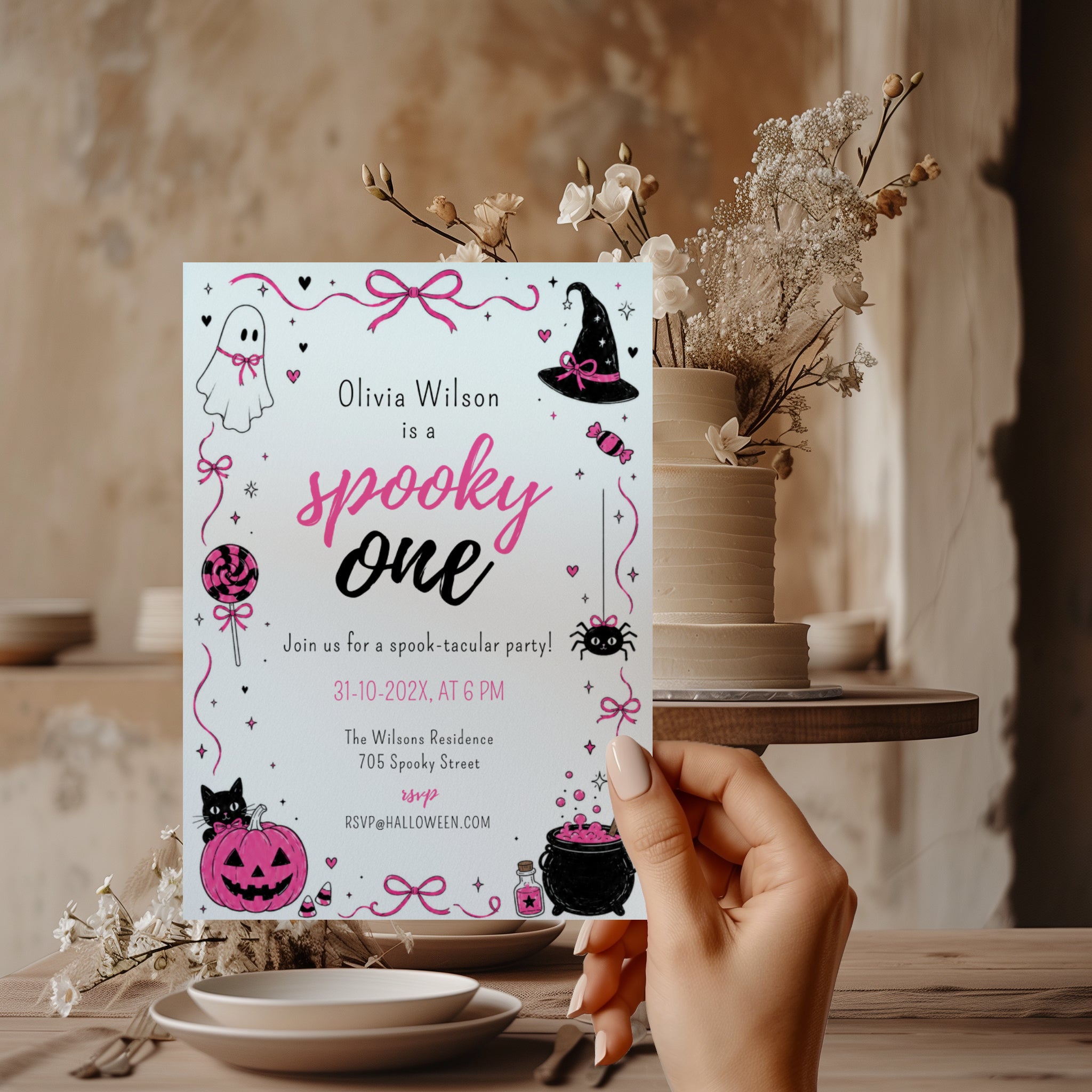 Spooky One first birthday girl invitation in pink and black with cute ghost, witch hat, spider, lollipop, pink pumpkin and bubbling Halloween cauldron illustrations.
