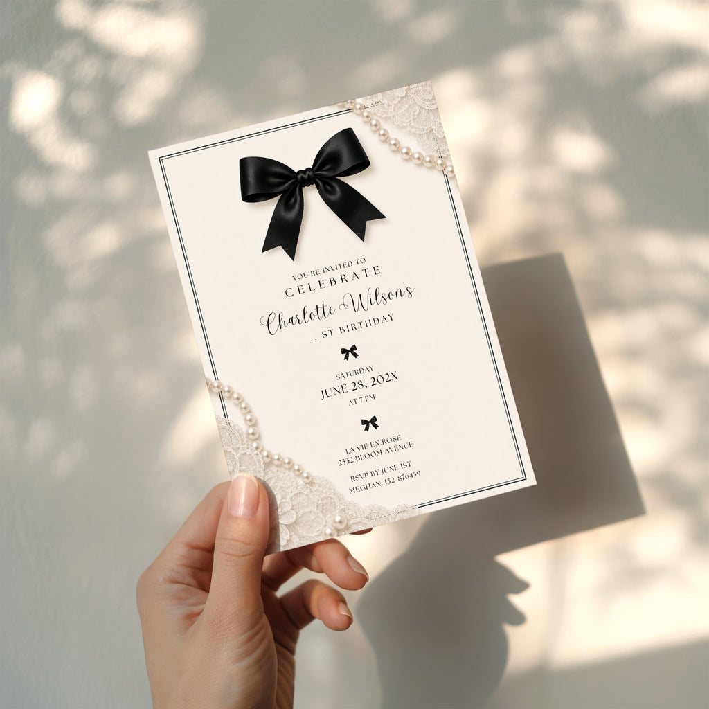 Elegant black bow birthday invitation with ivory background, pearl details and delicate vintage inspired lace accents.